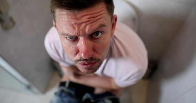 Emotionally portrait of man with bowel problems sits on toilet. constipation hemorrhoids diarrhea
