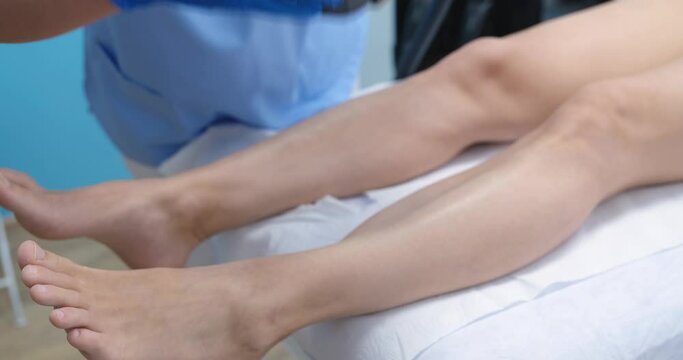 Beautician removes hair on female legs closeup. Hair removal body treatment