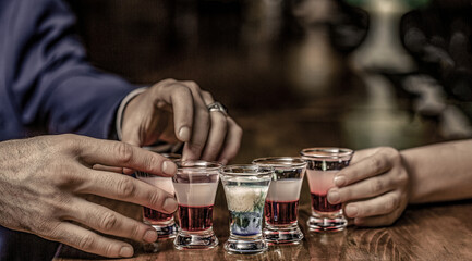 Multicolored shots on the bar. Friends drink shot or liqueur. Group friends tequila shot glasses in...