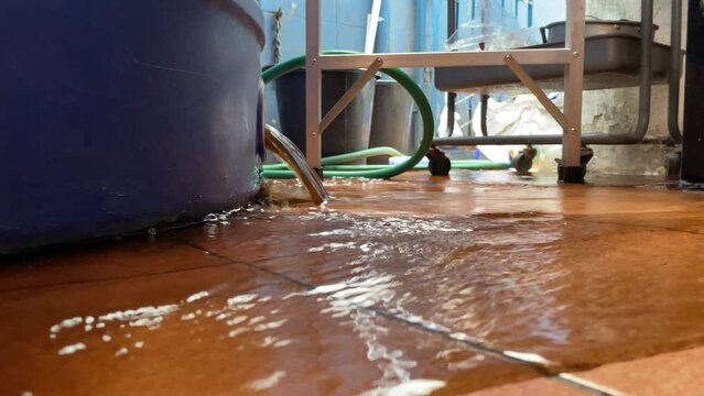 Dirty water drain from plastic tank at home on ground floor daytime. Routine maintenance. Hygiene and and clean water concept