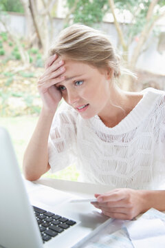 Upset Woman Holding Credit Card Looking at Laptop Screen
