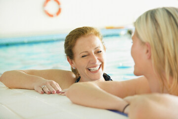 Two Women in Indoor Swimming Pool Smiling
