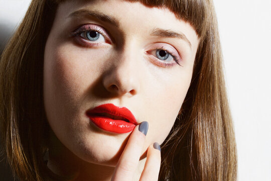 Close up of Young Woman with Red Lips Touching Corner of Mouth
