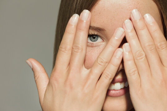 Woman with Hands over Eyes Smiling

