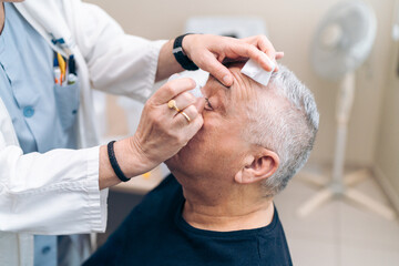 Doctor preps patient for glaucoma laser surgery with anesthetic.