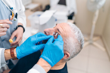 An expert fits a device to keep the eye open for laser therapy.