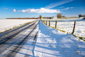 Paysage d'hiver. Route de campagne enneigée avec verglas à travers prairies et champs