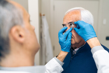 A doctor is fitting a speculum on a patient before glaucoma laser therapy.