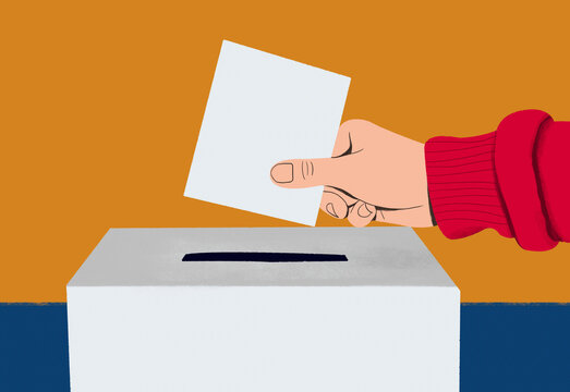 Close up hand of voter placing ballot in ballot box on election day
