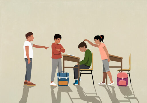 School kids bullying, picking on boy at desk in classroom
