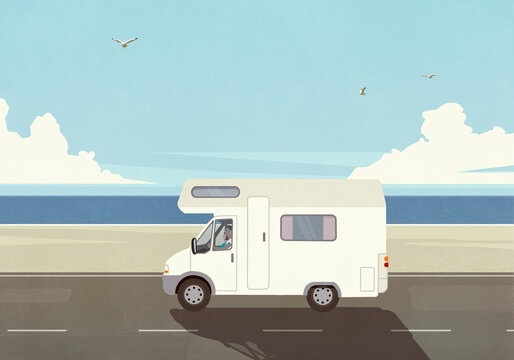 Man on vacation driving camper along sunny, summer ocean beach
