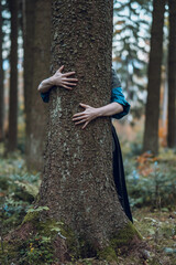 Young woman hugging a tree in the forest of Bavaria, Germany. Concept for nature, health and the environment.