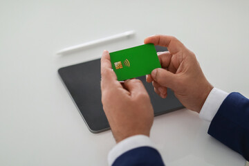 Close-up of a businessman's hands carefully examining a green bank card