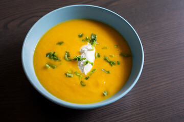 delicious carrot soup in a bowl with cream and green onion close-up