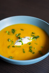 delicious carrot soup in a bowl with cream and green onion close-up
