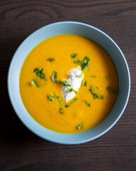 delicious carrot soup in a bowl with cream and green onion close-up