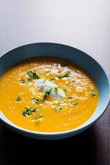 delicious carrot soup in a bowl with cream and green onion close-up