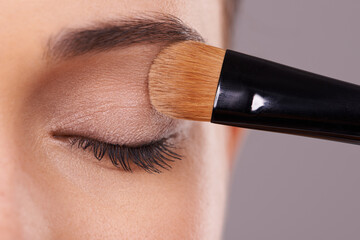 Closeup, eyelash and brush for eyeshadow with woman, makeup and beauty with application on purple...