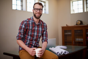 Portrait, laptop and architect in office with smile for career in construction industry and coffee. Man, contractor and entrepreneur of startup, small business and blueprint with floor plan on desk - obrazy, fototapety, plakaty