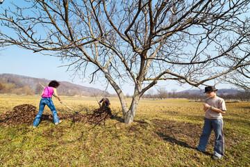 Family spring cleaning with rake in an orchard