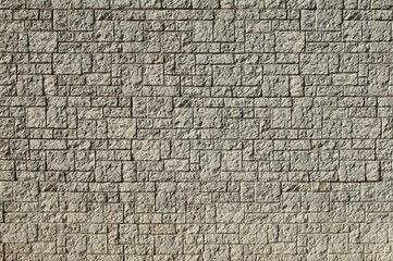 Large concrete wall made of different shaped tiles imitating rough stone. Background and texture