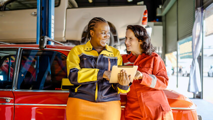 Team of mechanic two woman holding tablet computer in uniform talking about future repairs while...