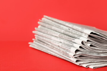 Stack of newspapers on red background, closeup. Journalist's work