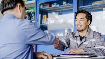 Professional vehicle maintenance man holding clipboard and talk with asian man customer at car service garage. Car repair and customer service concept, Discussing the cost of car repairs at the desk