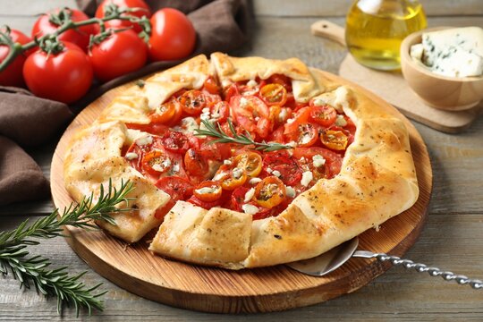 Tasty galette with tomato, rosemary and cheese (Caprese galette) on wooden table, closeup