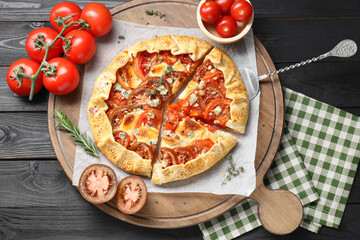 Tasty galette with tomato and cheese (Caprese galette) on black wooden table, top view