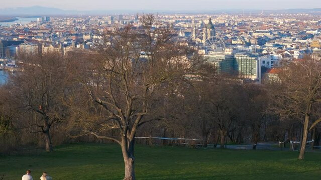 View from the spring park to the panorama of the city. A loving couple rests on a tava on an observation deck overlooking Budapest on a sunny day.