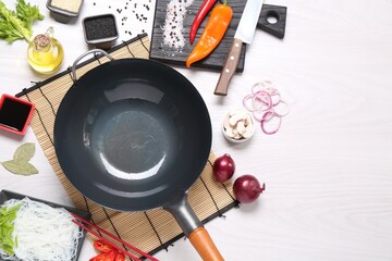 Wok, chopsticks and different products on white wooden table, flat lay. Space for text