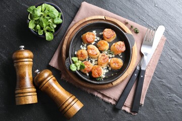Delicious fried scallops in dish served on dark gray textured table, flat lay