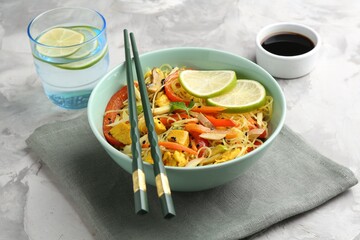 Stir-fry. Delicious cooked noodles with chicken and vegetables in bowl served on gray textured table