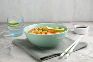 Stir-fry. Delicious cooked noodles with chicken and vegetables in bowl served on gray textured table