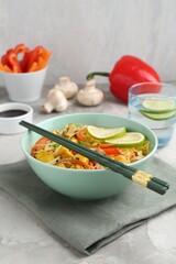 Stir-fry. Delicious cooked noodles with chicken and vegetables in bowl served on gray textured table