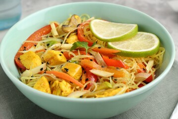 Stir-fry. Delicious cooked noodles with chicken and vegetables in bowl on table, closeup