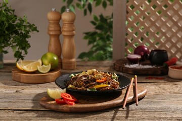 Stir-fry. Tasty noodles with meat and vegetables served on wooden table