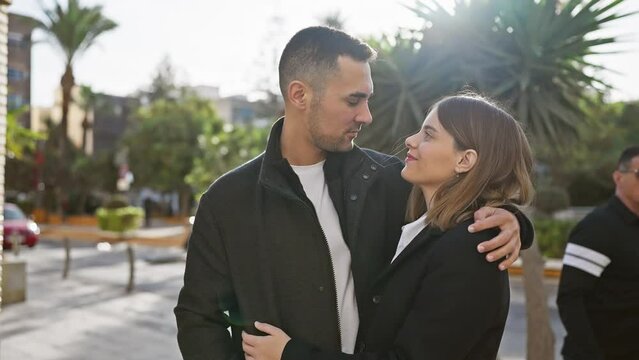 Couple embracing affectionately on a sunny urban street, capturing the essence of love and togetherness in a city environment.