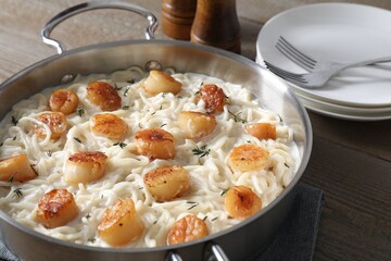 Delicious scallop pasta served on wooden table, closeup