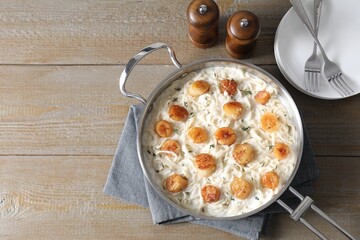 Delicious scallop pasta served on wooden table, flat lay. Space for text