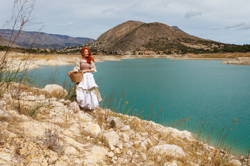 Retrato de mujer vestida de campesina de epoca con paisaje del embalse amadorio con escaso nivel de agua por el cambio climatico, España