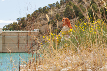 Mujer atractiva entre flores y malezas disfrutando de las vistas y calma en el embalse de Amadorio, Orxeta, Espa&ntilde;a