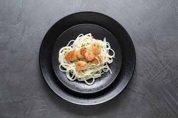 Delicious scallop pasta with green onion on grey table, top view