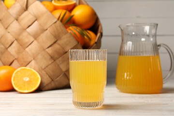 Tasty freshly made orange juice on white wooden table