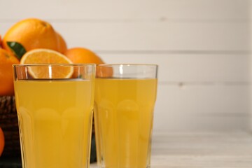Tasty freshly made orange juice on white wooden table. Space for text