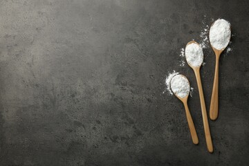 Baking powder in spoons on grey textured table, flat lay. Space for text