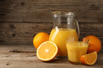 Tasty fresh oranges and juice on wooden table, space for text