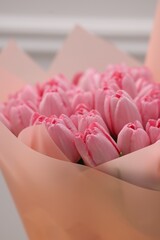 Bouquet of beautiful pink tulips near white wall, closeup