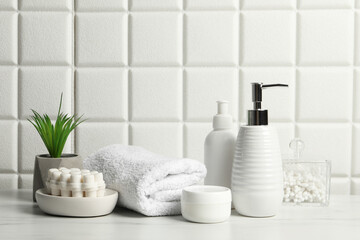Obraz na płótnie Canvas Different bath accessories and personal care products on white table near tiled wall